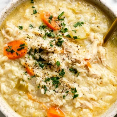 Bowl of delicious homemade chicken rice soup with herbs and vegetables.