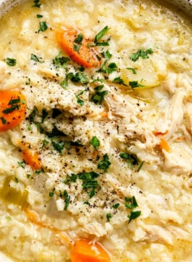 Bowl of delicious homemade chicken rice soup with herbs and vegetables.