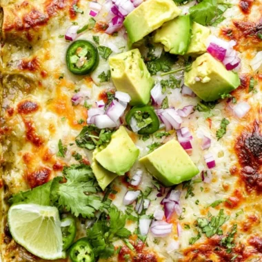 Cozy green chicken enchilada casserole topped with cheese and fresh herbs