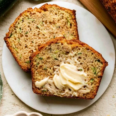 A slice of Greek Yogurt Zucchini Bread on a wooden table, showcasing its moist texture.