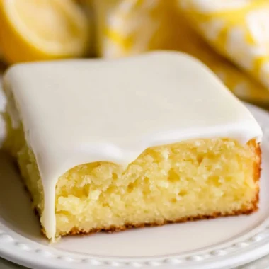 A slice of lemonade cake garnished with lemon slices and frosting.