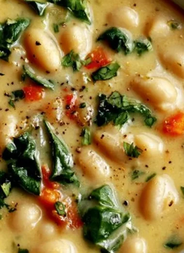Bowl of high protein white bean soup garnished with fresh herbs