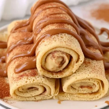 Cinnamon Roll Protein Crepes topped with cinnamon and icing on a plate