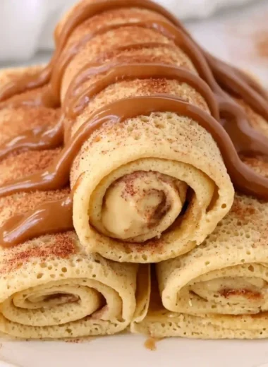 Cinnamon Roll Protein Crepes topped with cinnamon and icing on a plate