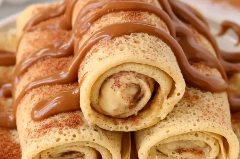 Cinnamon Roll Protein Crepes topped with cinnamon and icing on a plate