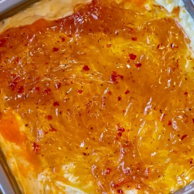 Baked Pepper Jelly Cheese Dip topped with herbs and served with crackers