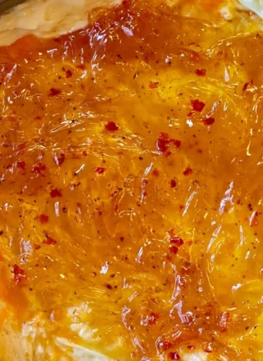 Baked Pepper Jelly Cheese Dip topped with herbs and served with crackers