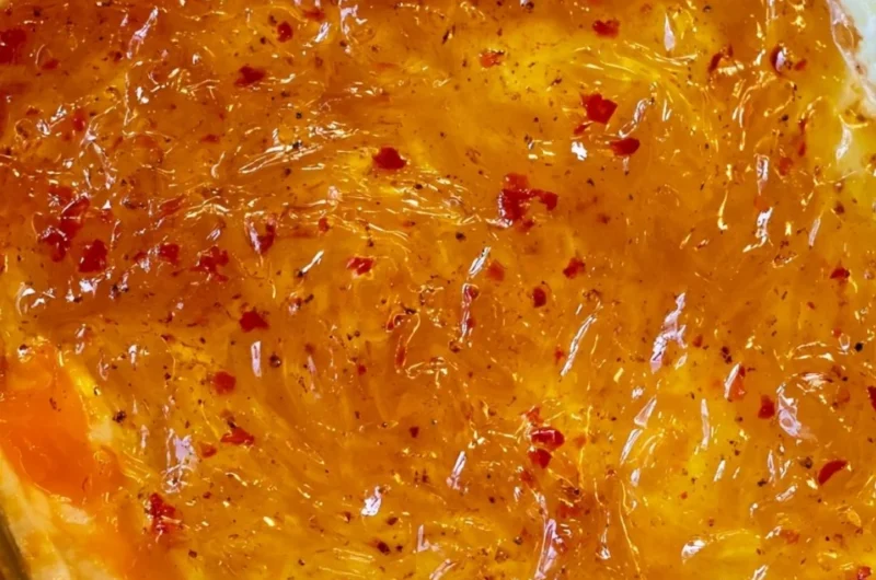 Baked Pepper Jelly Cheese Dip topped with herbs and served with crackers